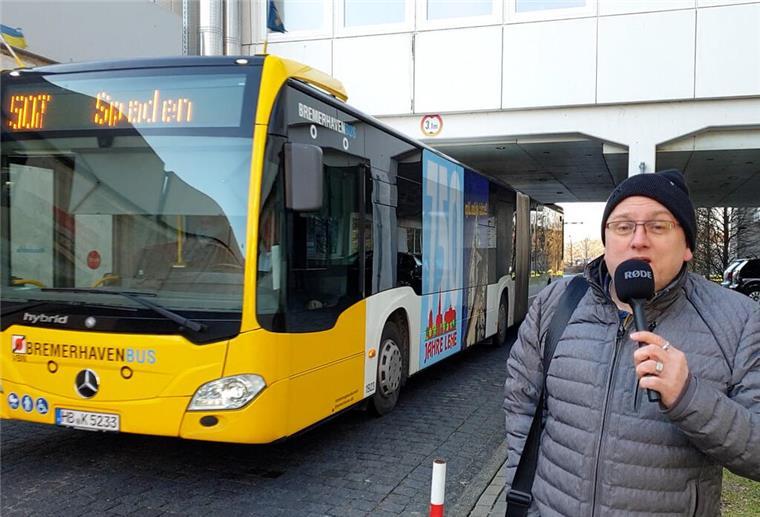 Bremerhaven: Neue Wasserstoffbusse wollen zu hoch hinaus Ein Reporter steht vor einem Bus, der unter einer Unterführung steht.