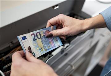 Eine Mitarbeiterin legt Geld in die Kasse 
