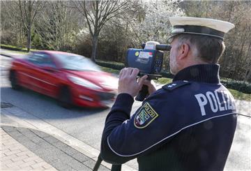  Ein Polizist misst mit einem Laserhandmessgerät (Laserpistole) während einer Geschwindigkeitskontrolle einen Autofahrer. 