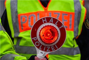 Ein Polizist hält eine Kelle mit der Aufschrift "Halt, Polizei" vor seinen Körper.