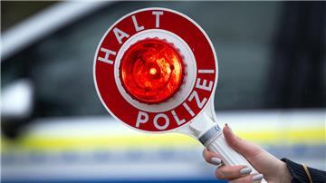 Eine Polizistin hält während einer Verkehrskontrolle eine Polizeikelle mit der Aufschrift "Halt Polizei".