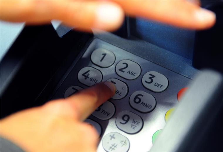 Diebe stehlen Senior EC-Karte - mehr als 38.000 Euro Schaden Eine Frau verdeckt das Eingabe-Pad eines Geldautomaten, um die Geheimzahl einzugeben.