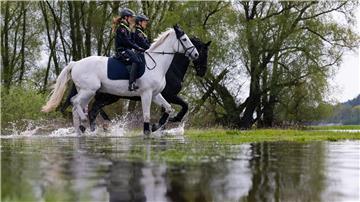 Die Polizeireiterin Lisa-Marie Schulz (l) und Anna Hartmann reiten mit ihren Dienstpferden am Ufer der Elbe entlang.