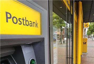 Eine Postbankfiliale von außen mit Geldautomaten im Vordergrund.