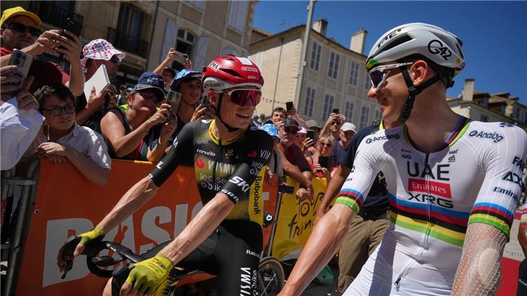 Die Rivalen Jonas Vingegaard (l) und der Slowene Tadej Pogacar (r) unterhalten sich vor dem Start.