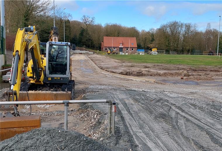 Die Bewässerung auf dem Sportplatz Bederkesa wirft Fragen auf Links steht ein kleiner gelber Bagger, hinter und neben ihm befindet sich eine Sportplatz-Baustelle.