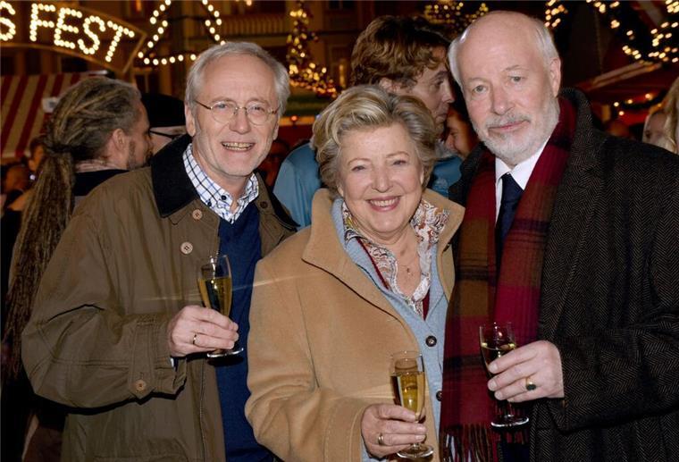 Vor fünf Jahren endete die „Lindenstraße“ Die Schauspieler Joachim Hermann Luger (Hans Beimer, links) und die Schauspieler Marie-Luise Marjan (Mutter Beimer) und Bill Mockridge (Erich Schiller, rechts) posieren in der Außenkulisse mit Sektgläsern nach der Live-Ausstrahlung der 1559. Folge im Dezember 2015.