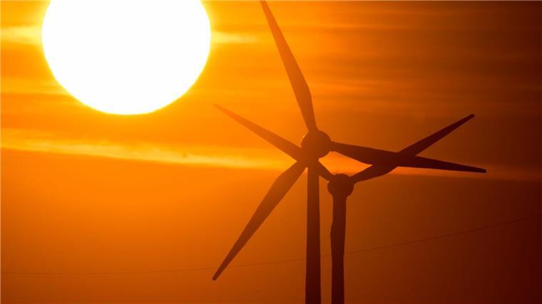 Statkraft will in Deutschland investieren Die Sonne geht hinter Windrädern auf.