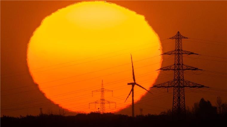 Weil fordert Energienetzausbau mit Steuergeld Die Sonne geht hinter Windrädern und Hochspannungsleitungen in der Region Hannover auf.