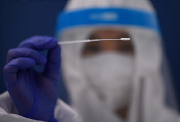 Die Standortleiterin hält im Corona-Testcenter im Gewerbepark Kadruf einen Corona-Teststab.