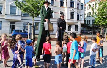 Die Stelzenläufer werden auf dem Leher Pausenplatz bei ihrem Marsch zur Theo sofort von Kindern umringt.