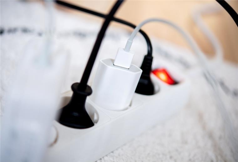Bundestag beschließt Energiepreisbremsen Die Netzstecker mehrerer Elektrogeräte stecken in einer Steckdosenleiste in einem Wohnzimmer.