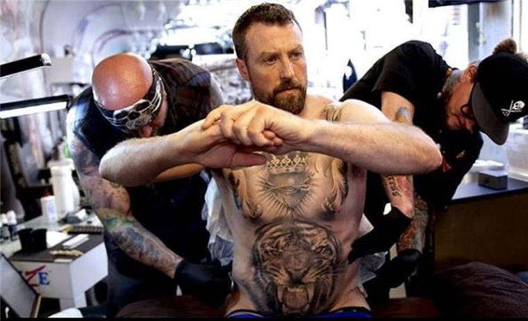 Die Tattoo-Künstler bearbeiten den Rücken von Andrew McPherson.