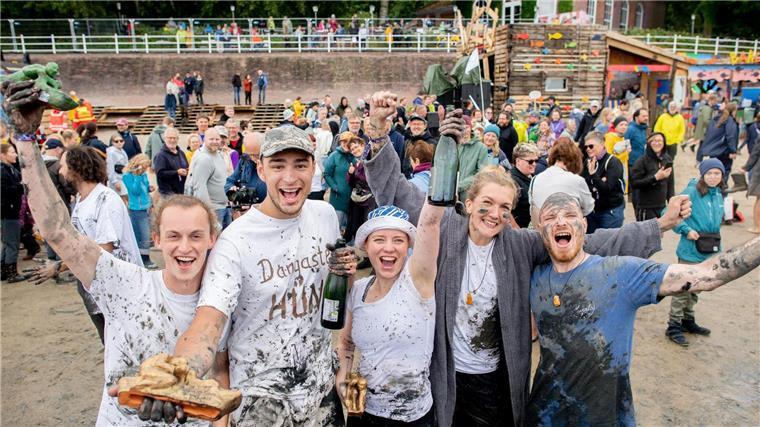 Deutsche Meister im Schlickrutschen gekürt Die Teilnehmerinnen und Teilnehmer „Das andere Wiesel“ (von links), „Dangaster Hüne“, „Aldi-Anna“, „Schlick-Schlack-Schlea“ und „Flo“ jubeln nach dem Finale der deutschen Meisterschaften im Schlickrutschen im Rahmen des Watt en Schlick Fest am Strand von Dangast.