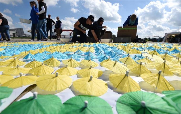 Weltrekordversuch für Cuxhavener Kinderhospiz: 30.000 Cocktailschirmchen werden in Sand gesteckt Die vielen Helfer stecken stundenlang unermüdlich die kleinen Schirmchen in den Strand.