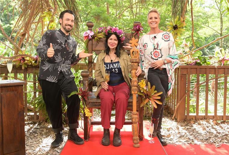 Die unerwartete Dschungelkönigin: Djamila Rowe gewinnt RTL-Camp Visagistin Djamila Rowe sitzt mit ihrer Krone nach dem Sieg beim RTL-Dschungelcamp 2023 auf ihrem Thron neben der Moderatorin Sonja Zietlow (r) und Moderator Jan Köppen.