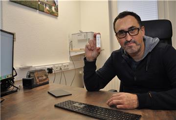 Das Bild zeigt Dr. Marc Hanefeld mit einer Impfdosis in der Hand.  