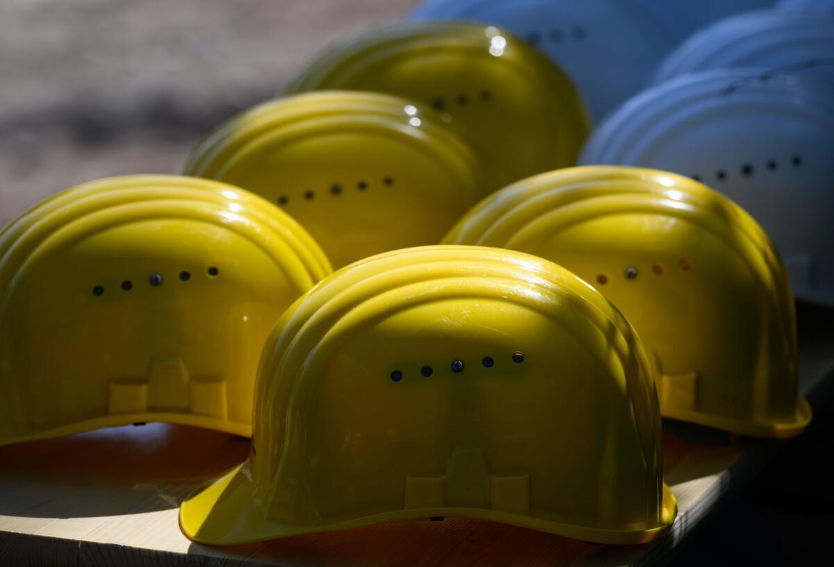 Mehrere gelbe Schutzhelme liegen auf einer Bank.