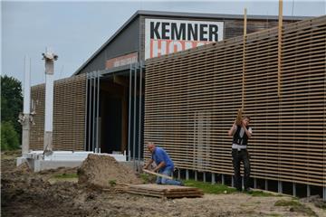 Die Zimmerleute haben schon ganze Arbeit geleistet. An der rückwärtigen Front des Möbelhauses ist die neue Lamellenstruktur gut zu erkennen, auch manche Pfeiler für die Werbe-Würfel stehen bereits.