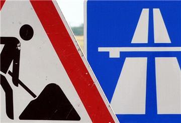 Ein Baustellenschild ist vor einem Autobahnschild platziert.  Die Zufahrt von der A1 auf die A261 Richtung Hamburg ist am Wochenende gesperrt.