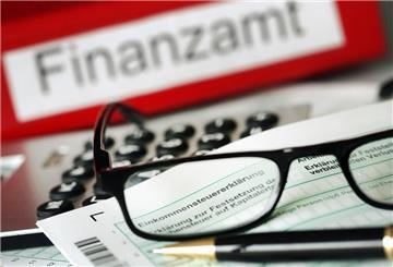  Auf einem Vordruck für die Steuererklärung liegen vor dem Aktenordner mit dem Aufdruck «Finanzamt» ein Stift und eine Brille. 