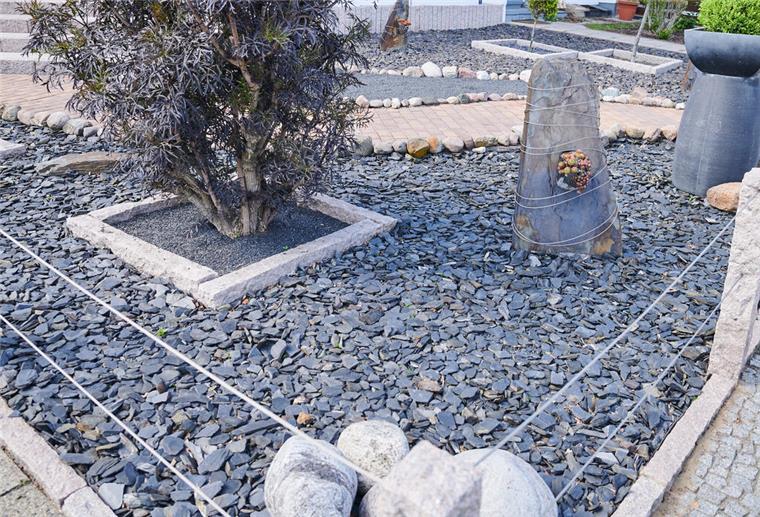 Vorgarten aus Kieselsteinen mit einigen Inseln aus Pflanzen.