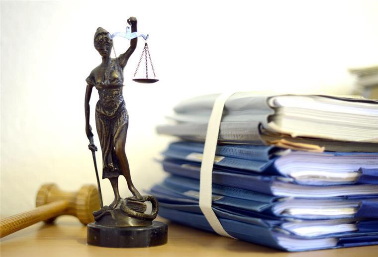 Kein Gehalt wegen Tattoo! Urteil bei Pflegekraft sorgt für Wirbel Die modellhafte Nachbildung der Justitia steht im Raum eines Richters des Landgerichts neben einem Holzhammer und einem Aktenstapel.