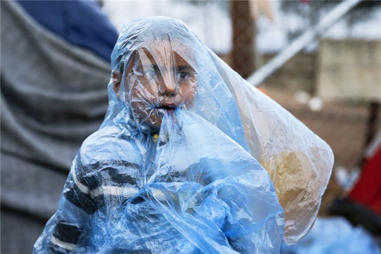 Regen und Schlamm im Elendscamp von Idomeni Dieses Kind muss sich im Lager von Idomeni vor Regen schützen.