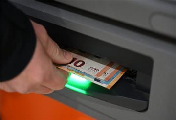 Ein Mann zieht Geldscheine aus dem Ausgabefach eines Geldautomaten