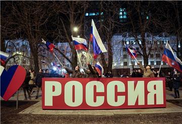 Donezk: Menschen schwenken russische Nationalflaggen und feiern hinter einem Transparent mit der Aufschrift „Russland“ die Anerkennung der Separatistengebiete in der Ostukraine durch Russland.