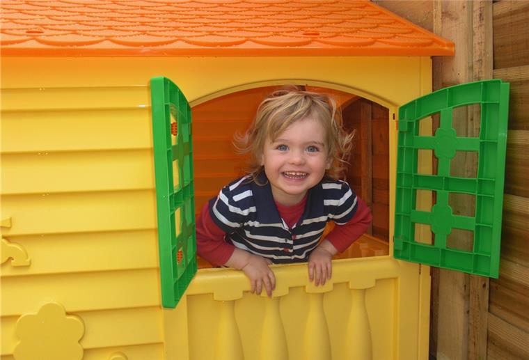 Spielhäuser zu gewinnen - So lässt du Kinderherzen höher schlagen! Kind sitzt im Garten