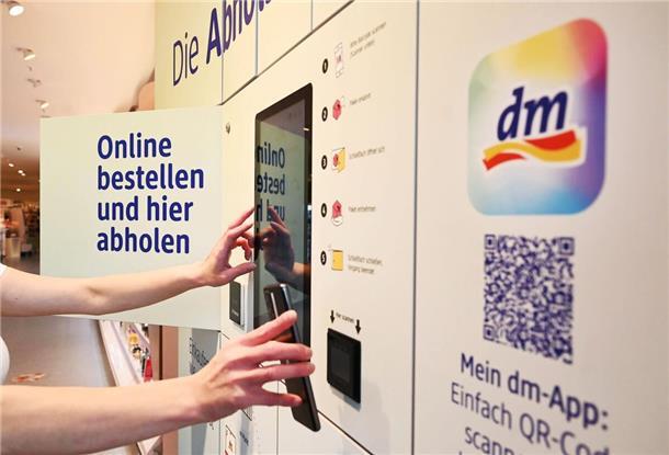 Eine Person steht in einer Filiale der Drogeriemarktkette dm an einer Abholstation.