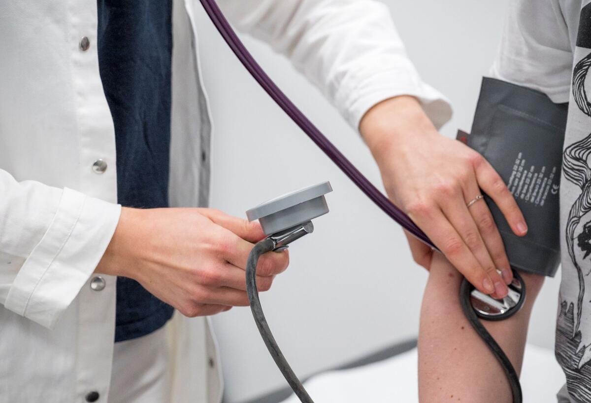  Arzt kontrolliert den Blutdruck und den Puls eines Patienten.