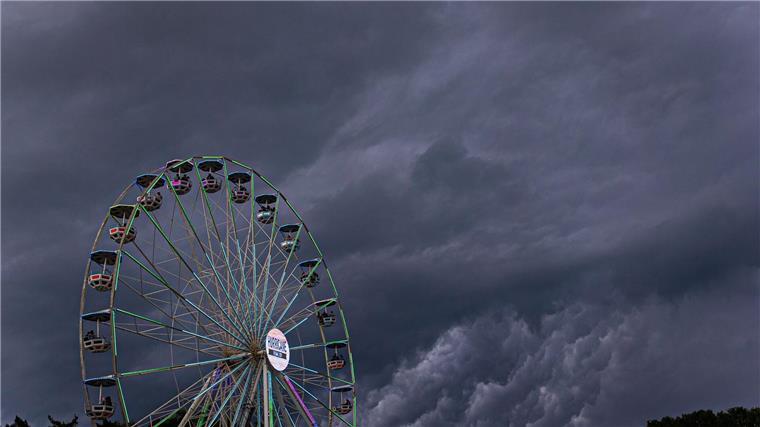 Dunkle Regenwolken ziehen über ein Riesenrad auf dem Gelände des Hurricane-Festivals in Scheeßel hinweg.