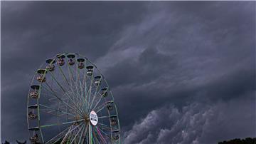 Dunkle Regenwolken ziehen über ein Riesenrad auf dem Gelände des Hurricane-Festivals in Scheeßel hinweg.