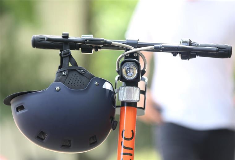 Polizeigewerkschaft: Fahrer von E-Scootern sollten Helme tragen Ein Elektro-Tretroller steht samt Helm fahrbereit auf der Straße.
