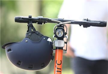 Ein Elektro-Tretroller  steht samt Helm fahrbereit auf der Straße.