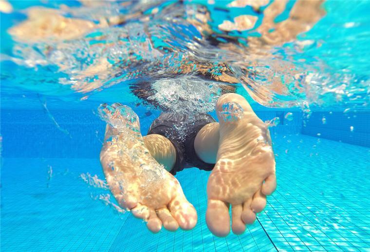 Bäder in Bremerhaven: Ärger mit defektem Bezahlsystem Symbolbild: Ein Schwimmer taucht durch klares Wasser in einem Schwimmbad.