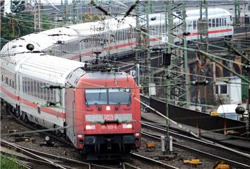 Zug  mit Lokomotive fährt durch Gleisfeld.