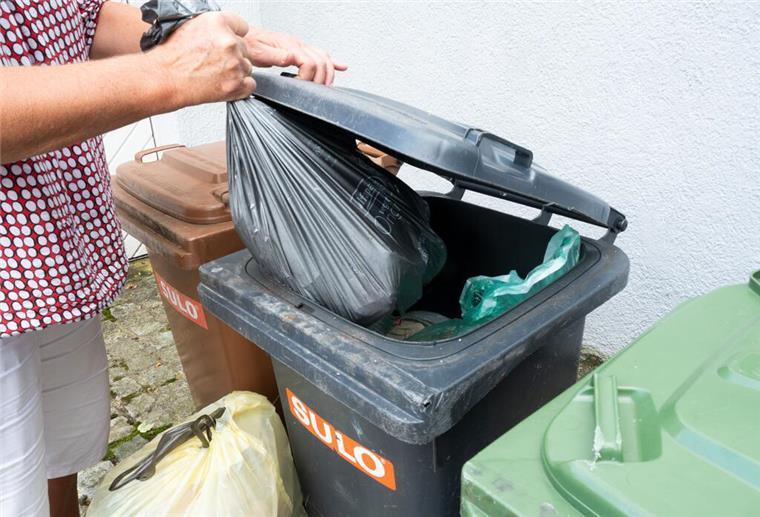 200 Euro Bußgeld! Wer gegen diese Müll-Regel verstößt, riskiert eine hohe Strafe Eine Frau wirft einen Sack mit Restmüll in eine graue Restmülltonne.