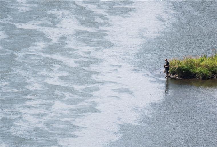 Niedrige Wasserstände wegen trockenen Wetters Ein Angler steht an der Weser.