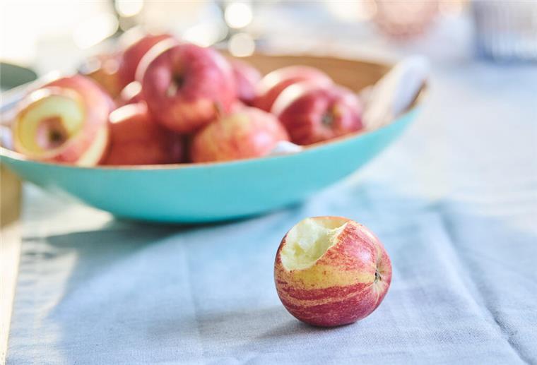 PRODUKTION - 03.01.2022, Berlin: Ein angebissener Apfel liegt vor einer Schale voller Äpfel. (gestellte Szene) Am 11.1. ist der Tag des Apfels. (Zu dpa: "Manch ein Biss mit Folgen: Was den Apfel so bedeutend macht") Foto: Annette Riedl/dpa +++ dpa-Bildfunk +++