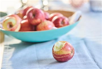 PRODUKTION - 03.01.2022, Berlin: Ein angebissener Apfel liegt vor einer Schale voller Äpfel. (gestellte Szene) Am 11.1. ist der Tag des Apfels. (Zu dpa: "Manch ein Biss mit Folgen: Was den Apfel so bedeutend macht") Foto: Annette Riedl/dpa +++ dpa-Bildfunk +++