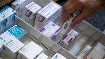 Ein Apotheker holt eine Medikamentenverpackung aus einer Schublade in einer Apotheke.