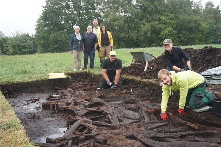 Archäologen finden in Karlshöfen Teil eines Moorwegs Ein Archäologenteam legt einen Streckenabschnitt des historischen Moorwegs frei. Im Hintergrund beobachten Dr. Stefan Hesse (hinten) und Dr. Marion Heumüller (rechts), Fachbereichsleiterin im Landesamt für Denkmalpflege, gemeinsam mit dem Ehepaar Specht die Arbeiten von Lennart Picht (rechts), Ingo Neumann und Jetta Harms.