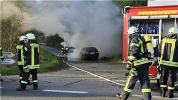 Feuerwehrmänner löschen einen Autobrand.  Ein Auto brannte am Dienstag in Drangstedt. Es kam zu Verkehrsbehinderungen auf der Landesstraße 120 durch Löscharbeiten.
