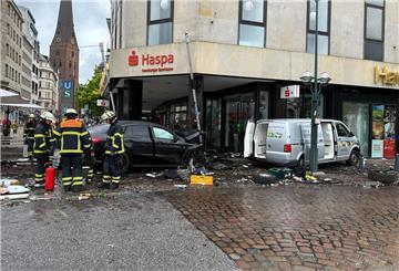 Helfer stehen an einem demolierten Auto vor einer Sparkasse. Ein Auto ist in Hamburg in eine Sparkasse gefahren, es gab mehrere Verletzte