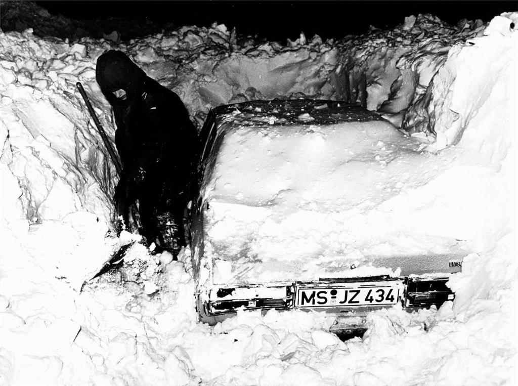 Ein Autofahrer schaufelt sein Auto frei.