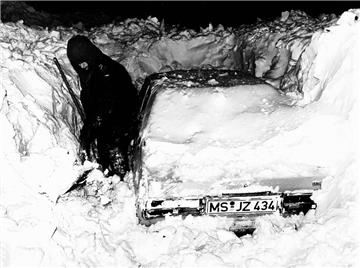 Ein Autofahrer schaufelt sein Auto frei.