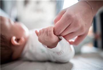 Ein Baby klammert sich an den Finger seiner Mutter.